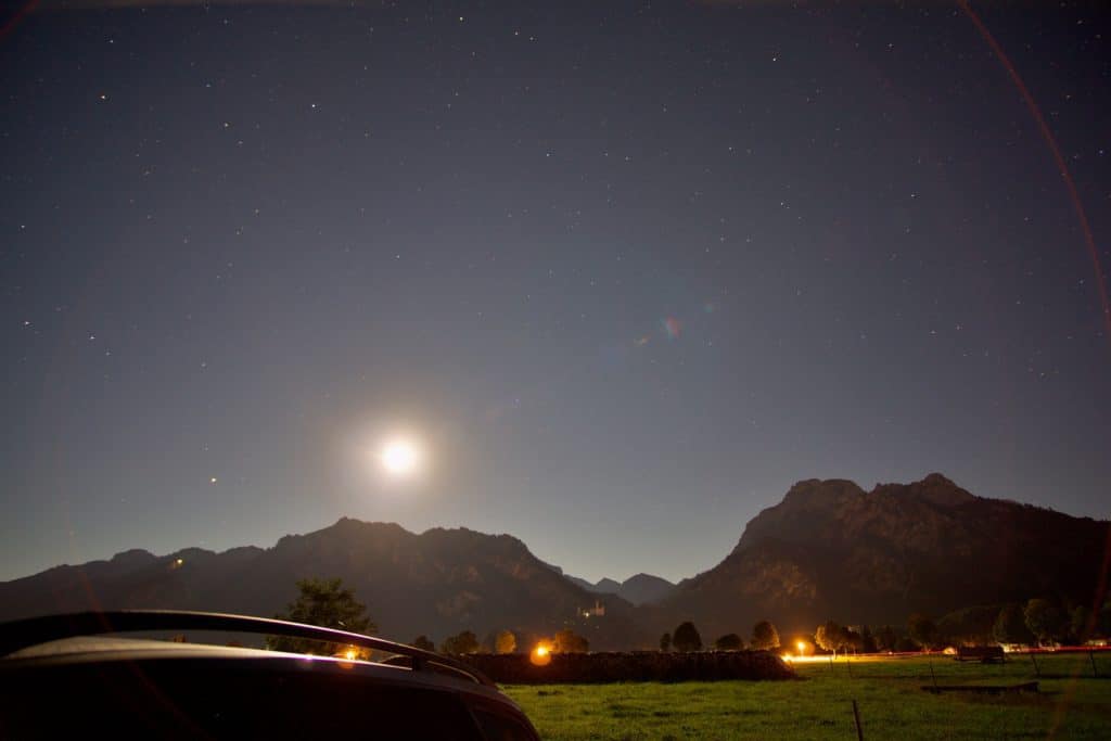 Im Auto schlafen und Astrofotografie um 23 Uhr mit Vollmond und Sternenhimmel über den Bergen im Ost-Allgäu und Schloss Neuschwanstein