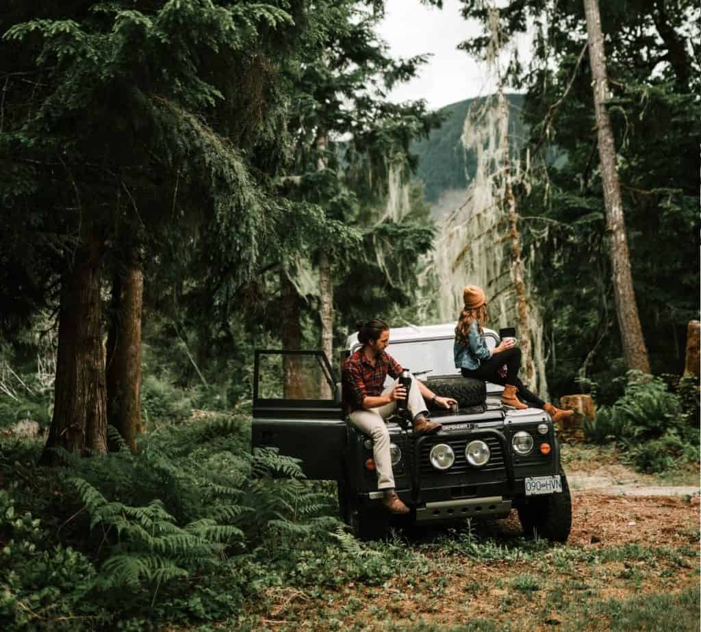 Land Rover Defender mit Personen im Wald